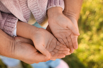 Father with his daughter holding hands outdoors, closeup. Family bonding