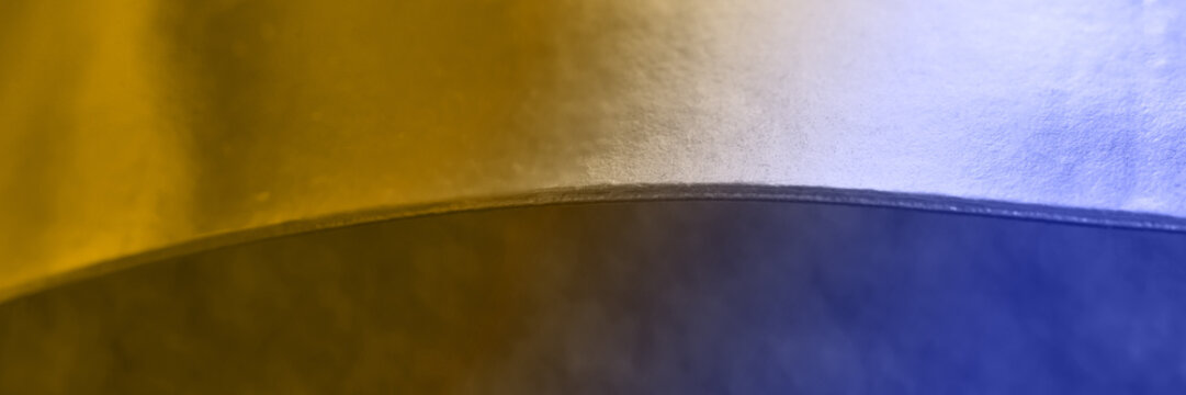 Abstract metallic surface with curved yellow and blue lighting effect. - Powered by Adobe