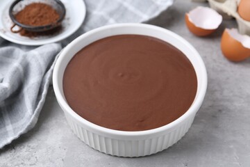 Liquid chocolate dough in bowl on grey table, closeup