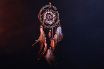 Beautiful dreamcatcher hanging in color lights against dark background