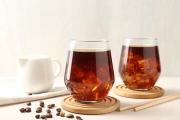 Tasty iced coffee and beans on white table