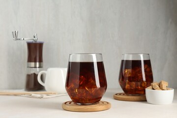Tasty iced coffee and sugar on white table
