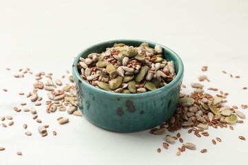 Mix of seeds in bowl on white table, closeup