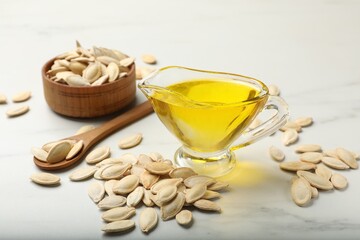 Pumpkin seeds and oil on white table, closeup