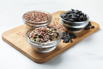 Different seeds in bowls on white table, closeup