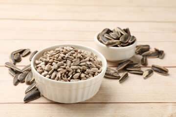 Peeled and unpeeled sunflower seeds on white wooden table