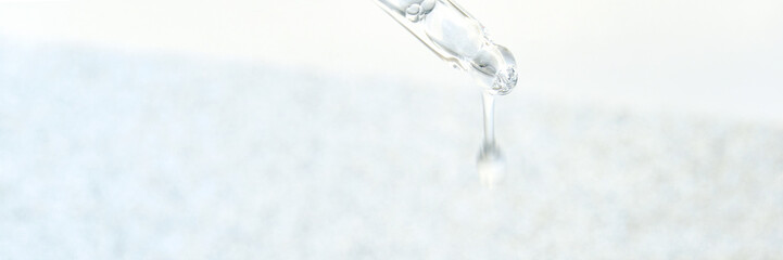 Close-up of pipette with clear liquid against light background in scientific laboratory setting.