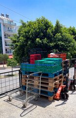 A product cart with stacked pallets and mesh containers filled with fruits and vegetables 