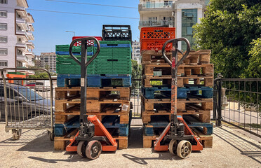 Product carts and pallets stacked with mesh containers at an outdoor market. 