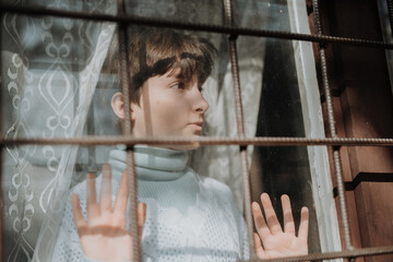 Poor sad orphan girl looking out of window.