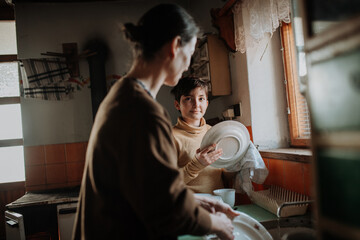 Girl helping mother to wash dishes in an old rural kitchen.