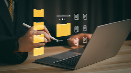 Businessman using digital file management system on laptop, organizing folders and documents in...