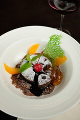 Delectable Chocolate Lava Cake Served on a White Plate, Garnished with Fruits and a Mint Leaf 