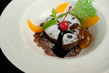 Delicious molten lava cake beautifully plated, adorned with fruit, mint leaves, and a dusting of powdered sugar