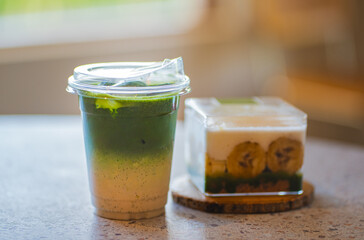 Close up glasses of ice matcha green tea and matcha banoffee on wooden tray of a coffee shop summer terrace, matcha menu photography.