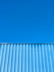 blue sky background. A blue corrugated iron roof touches a clear  blue sky. minimal picture, free space