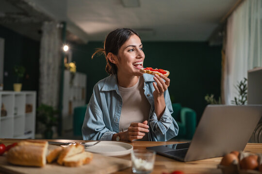 Happy woman eating breakfast working from home - Powered by Adobe