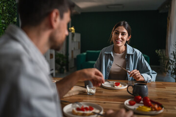 Couple enjoying healthy breakfast together talking at home