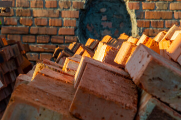 Bricks are neatly stacked at a construction site, illuminated by warm evening sunlight, ready for an upcoming building project