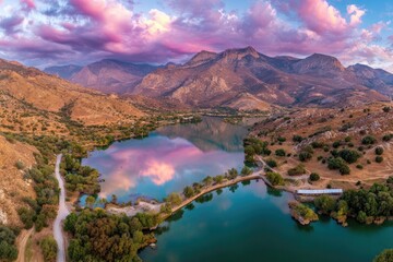 Aerial of a lake mirroring a vibrant sunset against rugged mountains