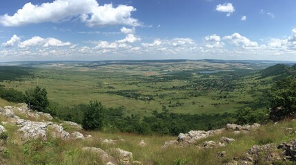 Panoramic view of a vibrant green valley with distant hills under a bright blue sky