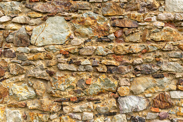 Close-up of an old stone wall made of irregular rocks and mortar, showcasing rustic texture and natural earthy colors. Perfect background or detail of traditional architecture.