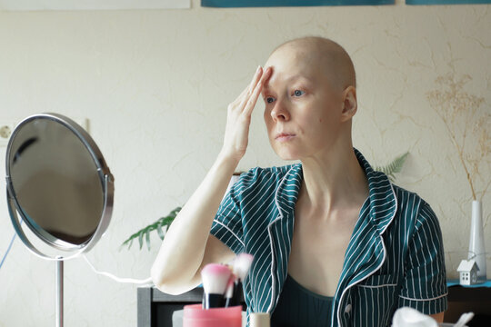 Woman recovering from cancer carefully applies facial serum in front of a mirror, showing gentle beauty and daily skincare for sensitive skin after therapy