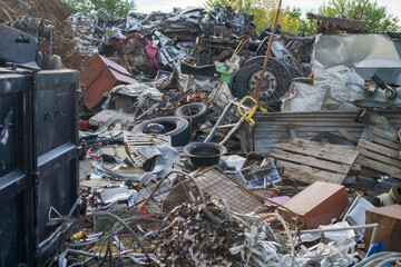 Large pile of mixed metal, machinery parts, and vehicle debris at an industrial scrapyard, showing recycling and waste management environment.