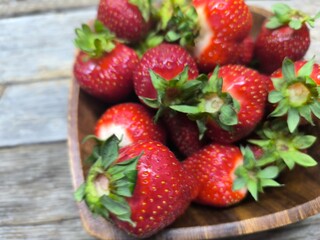 juicy ripe strawberries lie in a wooden plate