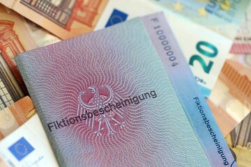 Fototapeta premium German temporary Permanent resident card specimen and euro money bills lies on wooden table close up. Fiktionsbescheinigung