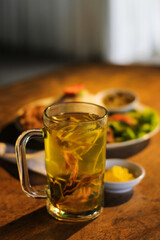 Description:
Warm traditional herbal ginger tea served in a glass mug on a wooden table. 