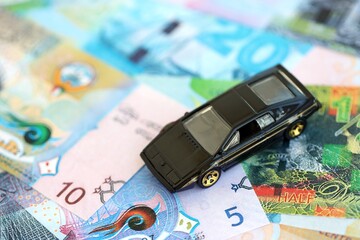 Kuwaiti dinar currency money bills and toy car close up. The concept of car ownership