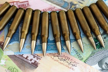 Bahraini dinar currency money bills and rifle bullets close up. The concept of warfare and gun selling