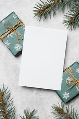 Blank Christmas holidays card mockup with wrapped green gifts adorned with snowflakes and twine, set against a textured gray background, perfect for holiday greetings and festive messages