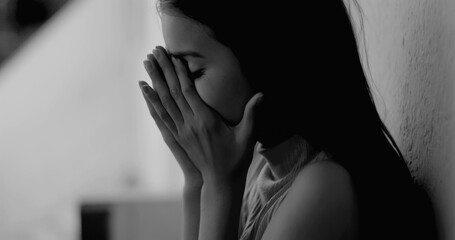 Young girl leaning against a wall, head in hands, overwhelmed by grief and emotional turmoil,...