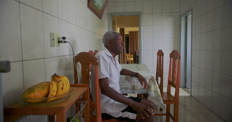 African American Elderly man seated at table with serene expression, radiating calm and...