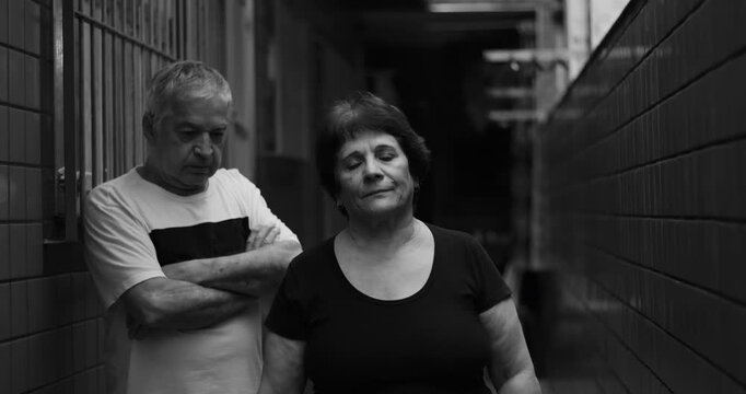 Elderly couple in hallway, silent treatment and avoiding eye contact, tension and unresolved conflict, emotional distance captured in dramatic and somber atmosphere