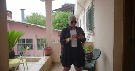 Close-up of African American woman’s hands with pink nails and gold jewelry using a smartphone,...