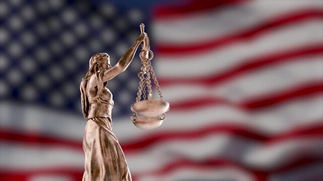 360 Degrees Rotating Seamless Looping Lady Justice Statue Over A Slow Motion American Flag Background.
