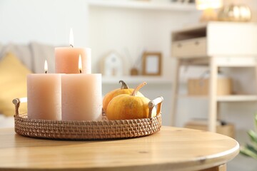 Burning candles and pumpkins on wooden table indoors, closeup. Space for text