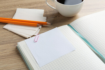 Blank notes, notebook, cup of coffee and pencils on wooden table, closeup. Space for text