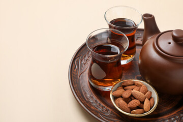 Traditional Turkish tea and almonds on beige table, closeup. Space for text