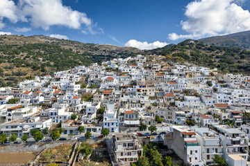 Aerial panoramic view of Filoti village in Naxos, Greece, captured by drone, showcasing the traditional whitewashed houses, winding streets, and beautiful mountainous landscape.
