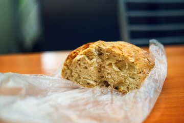 Half a round rustic bread loaf in plastic bag on table with several slices cut, ideal for food blogs and culinary content