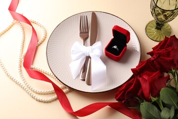 Beautiful table setting for romantic dinner, box with engagement ring and roses on beige background