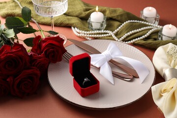 Beautiful table setting for romantic dinner, box with engagement ring and roses on color...