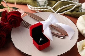 Beautiful table setting for romantic dinner, box with engagement ring and roses on color...