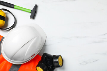 Different safety equipment and hammer on white marble table, flat lay. Space for text