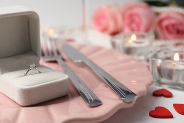 Beautiful table setting for romantic dinner and box with engagement ring on white background,...
