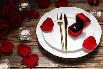 Beautiful table setting for romantic dinner, box with engagement ring and roses on wooden background